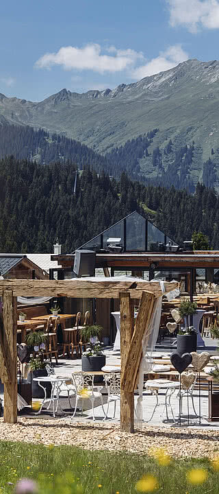 Vermala Wirt | Sommerterrasse & Hochzeitslocation in den Bergen – Silvretta Montafon Sommerliche Terrasse des Vermala Wirt mit Blumenwiese und dekorativen Herz-Elementen, perfekt für Hochzeiten und ruhige Auszeiten in den Bergen.