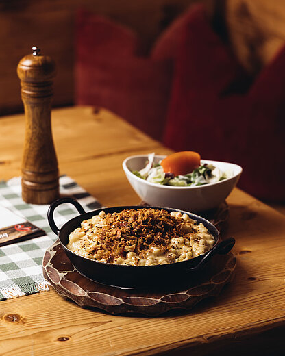 Frisch zubereitete Montafoner Käsespätzle mit Röstzwiebeln beim Vermala Wirt – perfekter Genussmoment beim Skifahren oder Wandern im Silvretta Montafon.